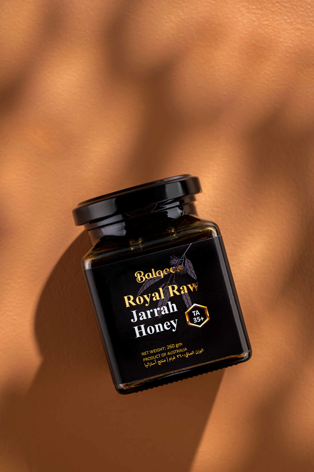 Jar of Royal Raw Jarrah Honey lying on orange stone in the sun