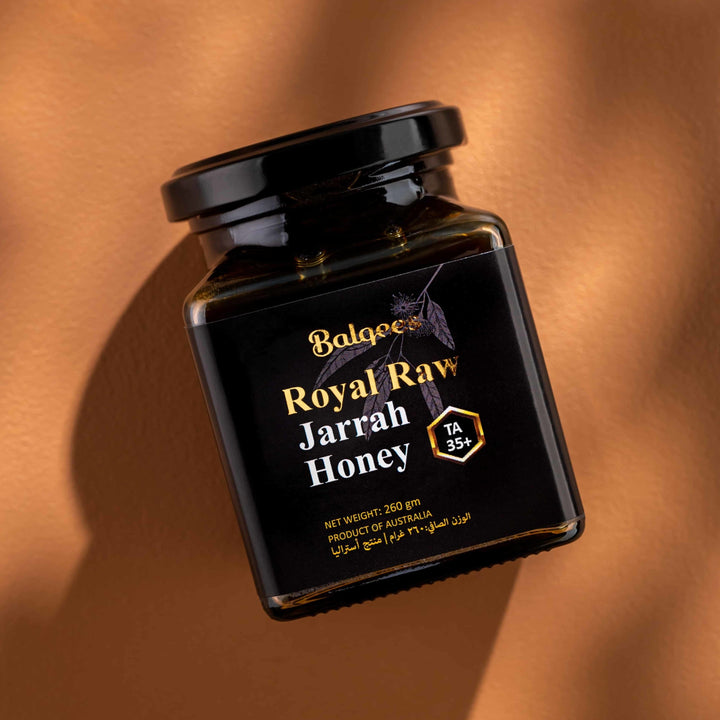 Jar of Royal Raw Jarrah Honey lying on orange stone in the sun